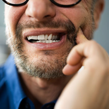 man touching painful tooth