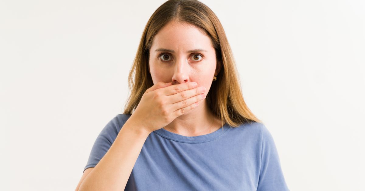 Woman covering mouth.
