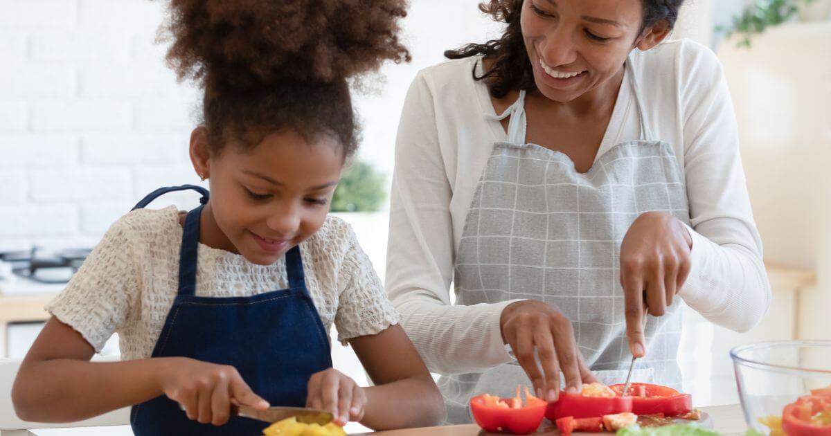 Mother and daughter chopping vegetables.