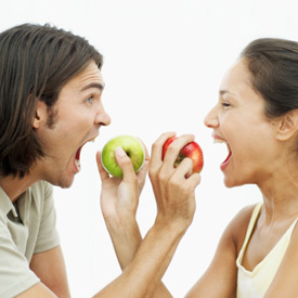 Young couple holding out apples for each other