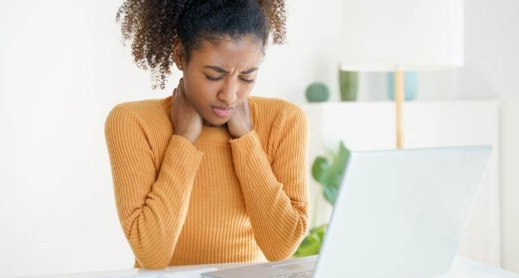 Woman grabbing neck while sitting.