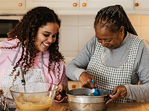 mother and adult daughter baking together in a kitchen