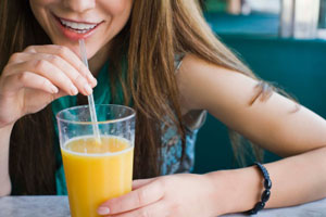Girl drinking orange juice with a straw