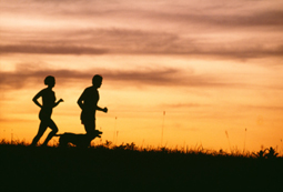 Man, woman and dog running at sunrise