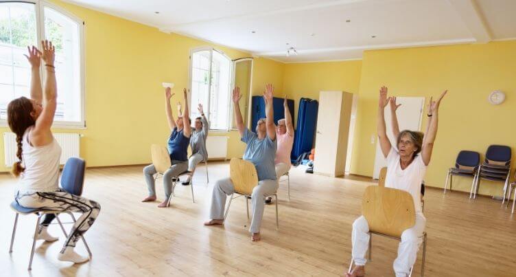 Older people practicing chair yoga.