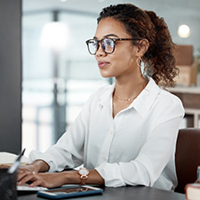 woman with glasses working at a computer