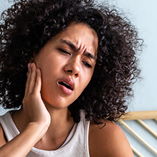 woman rubbing her jaw in pain