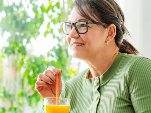 woman holding a glass of juice with a straw in it