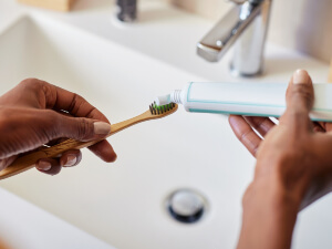 toothpaste being squeezed on toothbrush
