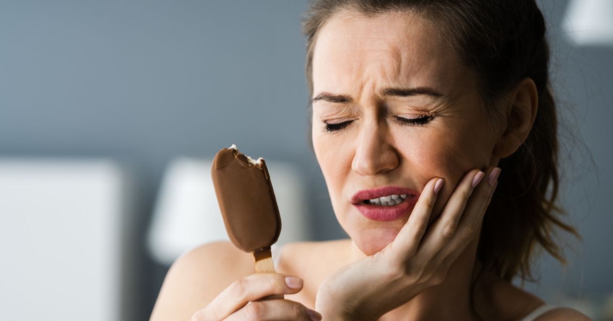 Woman wincing in pain from eating ice cream.