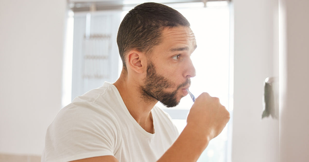 man brushing teeth with mouth closed