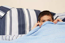 Boy hiding under his bed sheets