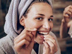 woman in a towel flossing her teeth