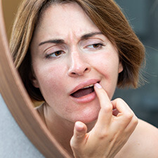 woman looking at her teeth in a mirror