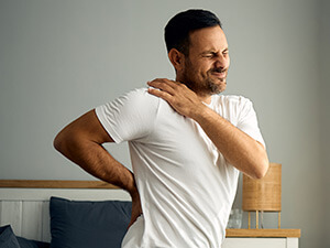 man sitting on a bed with back stiffness