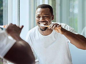 man brushing teeth in front of mirror