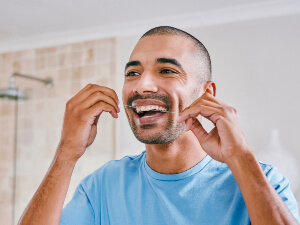 smiling man flossing teeth