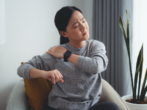 woman holding shoulder in pain