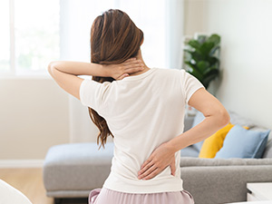 woman sitting on bed with back pain