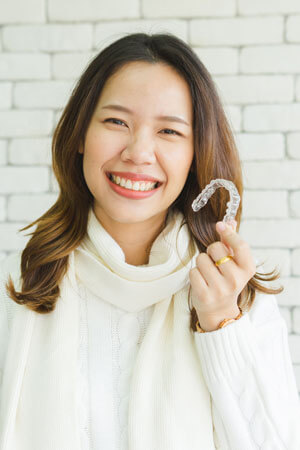 woman holding clear dental aligner