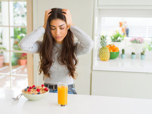 woman with headache in kitchen