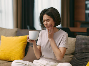 Woman on sofa with tooth pain