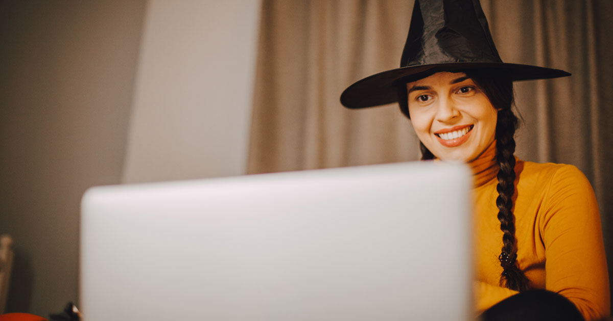 Woman wearing witch hat on computer