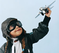 Young child in aviator outfit flying toy plane