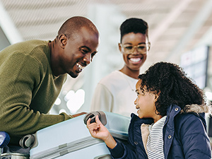 mom, dad, and kid in airport smiling at one another