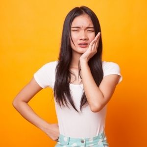 Woman grabbing jaw in pain.