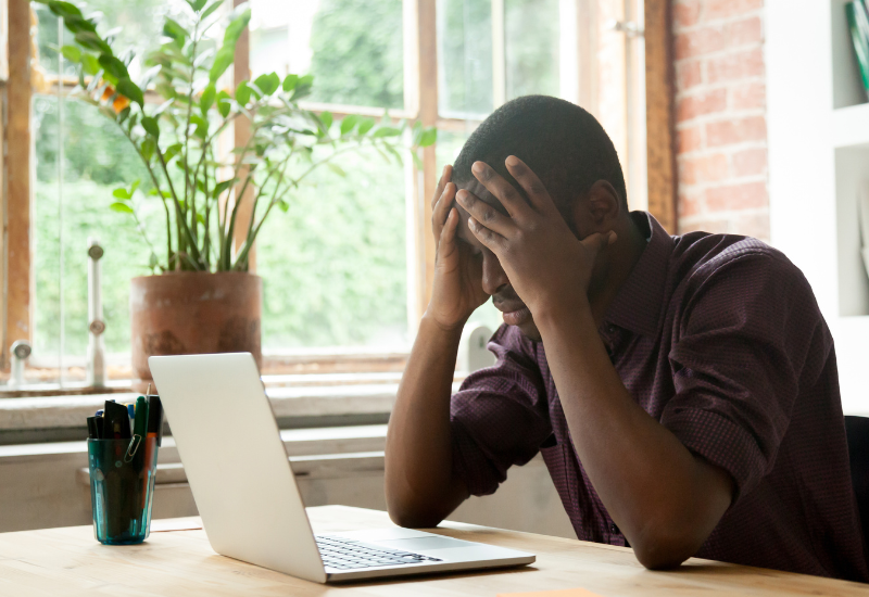 Man looking at computer, holding head