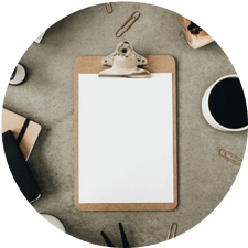 A desk top with a clipboard and a cup of black coffee