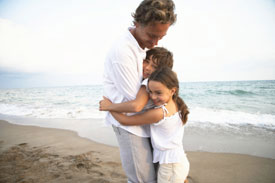 Children hugging man on beach