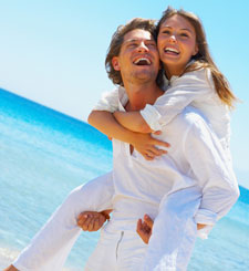 happy young couple piggybacking at beach