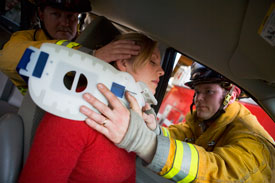 Woman being carried out of car by firemen
