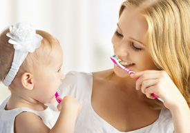 Mother and baby brushing teeth