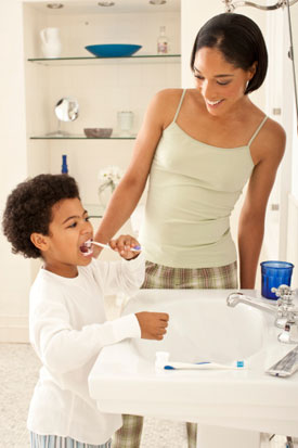 Mother helping son brush teeth
