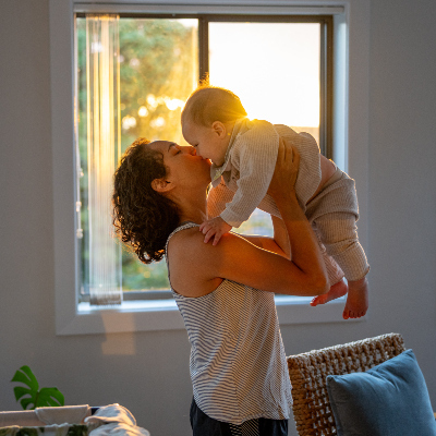 mom holding up baby and kissing its face