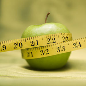 Green apple with measuring tape wrapped around it