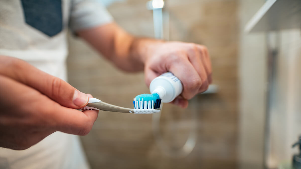 Putting toothpaste on brush