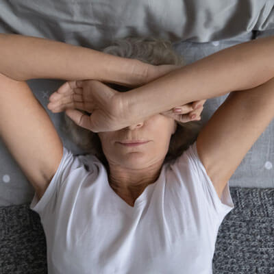 woman arms covering face lying on bed