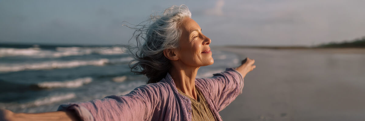 Person with arms spread wide on beach, free from pain