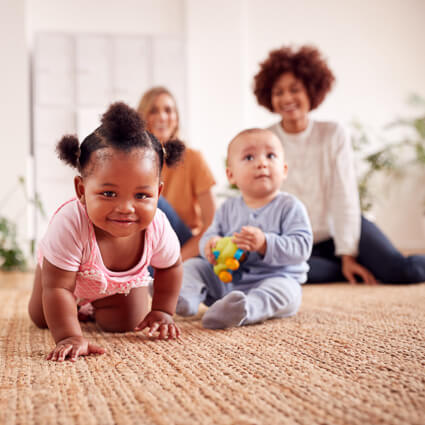babies playing on floor while moms watch