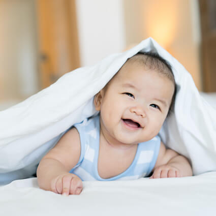 Smiling baby under a blanket