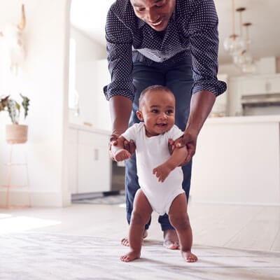 father teaching his young baby to walk