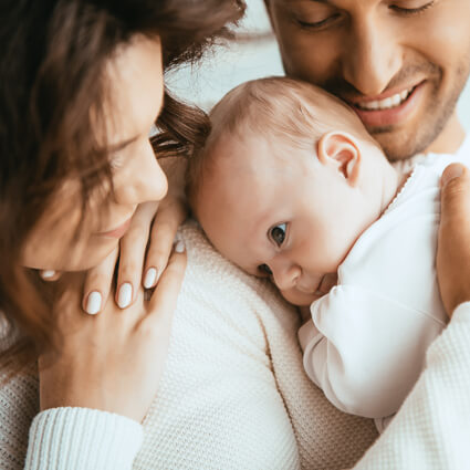 baby on dads shoulder with mom lookin on