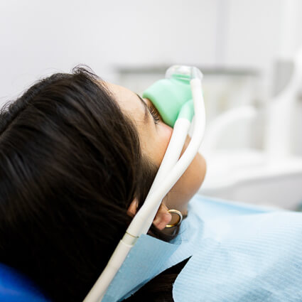 woman with nitrous oxide mask on her face during dental visit