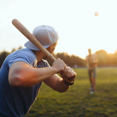 man playing baseball at sunset