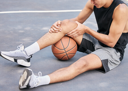 basketball player sitting on floor with knee pain