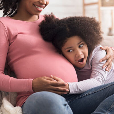 big sister listens to baby in tummy